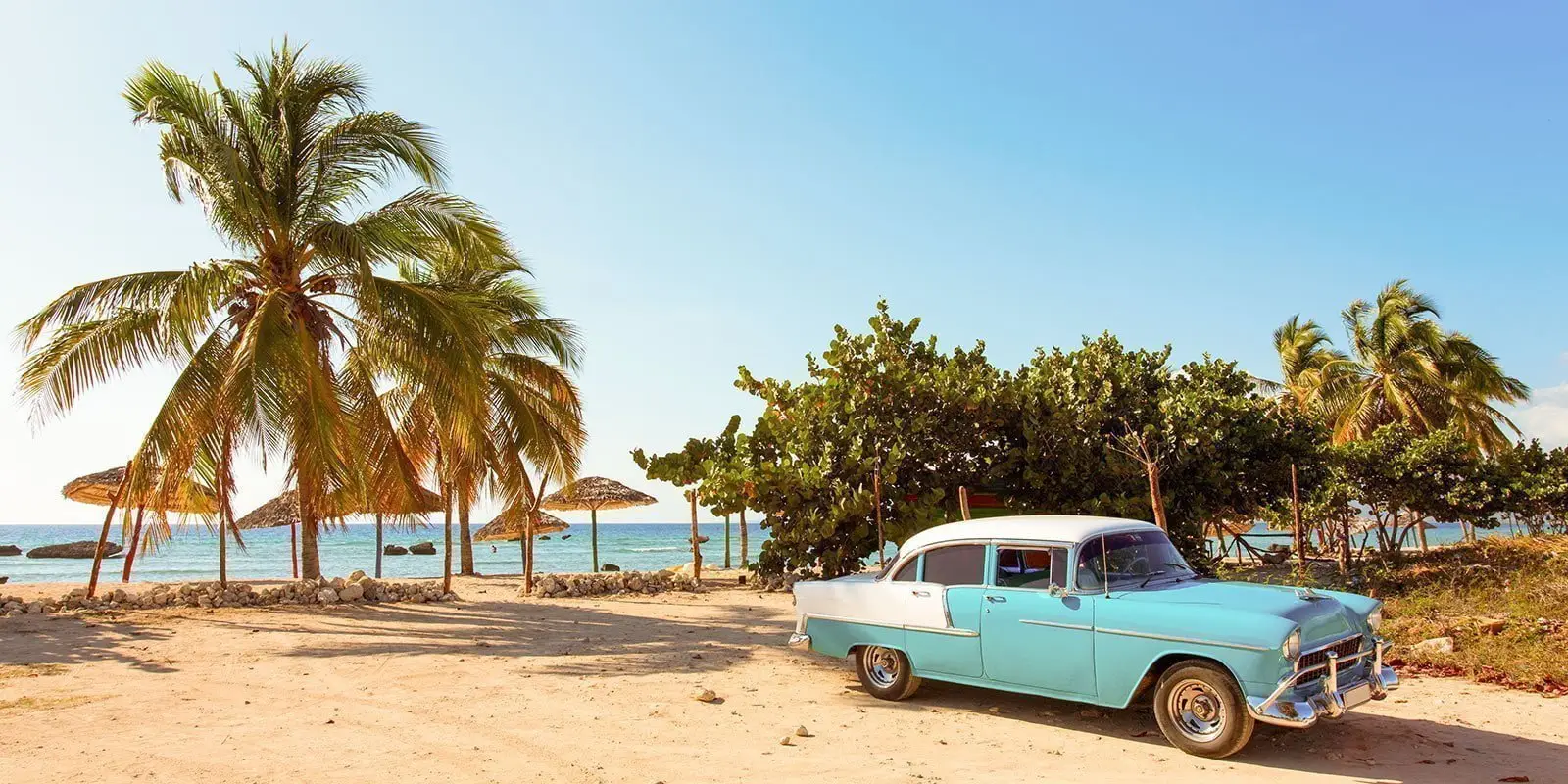 blue classic car parked on a beach in Havana